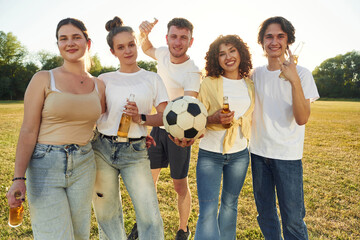 Males and females. Young friends are having fun on the field with soccer ball