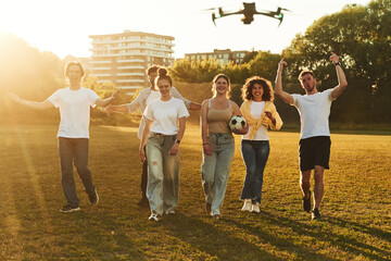 Drone is flying. Young friends are having fun on the field with soccer ball