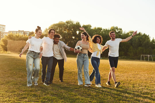 Getting ready for playing football. Young friends are having fun on the field with soccer ball