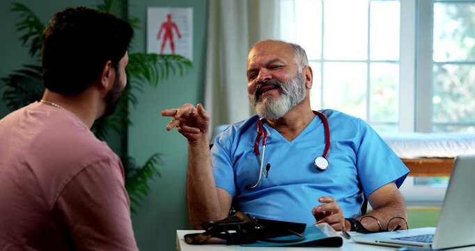 Indian doctor patient doing high five in happiness after successful recovery as experienced male physician celebrates with young man inside modern Indian clinic OPD healthcare visit