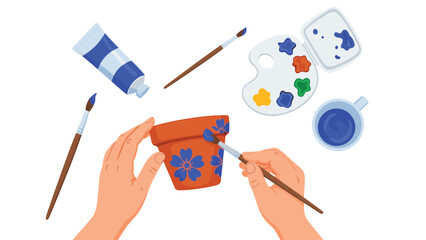 Creative hands meticulously painting delicate blue flowers onto a terracotta pot, surrounded by various art supplies, illustrating a relaxing pottery hobby.