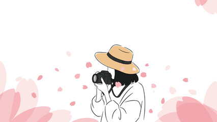 Person wearing a straw hat taking a photograph with a dslr camera among falling pink cherry blossom petals in a spring garden setting.