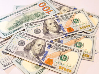 Stack of US hundred dollar bills scattered on a white background. Symbol of wealth, finance, savings, investment, success, and global economy, ideal for business and money concepts.