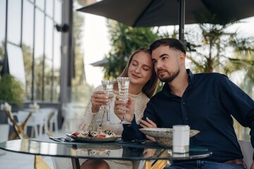 Celebrating, knocking glass. Couple enjoying date in the outdoor restaurant