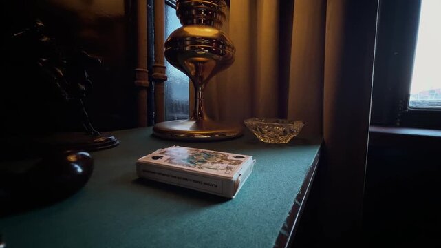 Classic interior. Vintage and antique items on a table with a cloth cover. Table lamp, lighter, cigarette case, pipe, ashtray, playing cards, statuette
