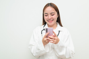 Portrait of young Asian female doctor against white background using phone texting and smiling