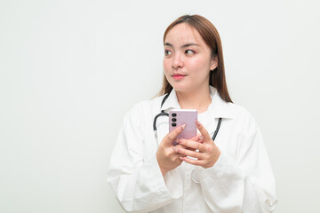 Portrait of young Asian female doctor against white background using phone thinking