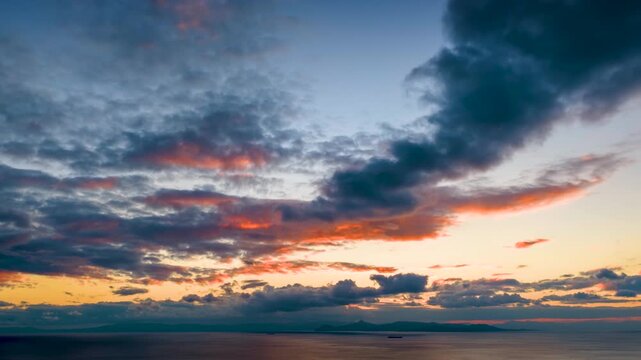 Time lapse view of a cloudy sunset over the sea with orange and blue colors as a background or texture