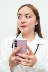 Portrait of young Asian female doctor against white background using phone thinking