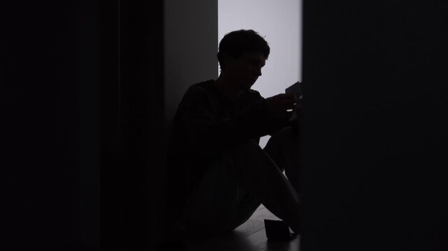 Man counting money from wallet after financial stress, lonely silhouette sitting on floor in dark corridor, lack of cash, personal finance problems and economic pressure