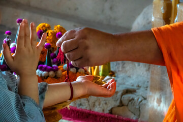Senior monk attaching a red buddhist bracelet string during a ceremony in Wat Chomphet, on top of a hill across the Mekong River from Luang Prabang, Laos