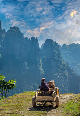 A farmer on a tractor wiith stunning karst mountain scenery in the background, Vang Vieng,...