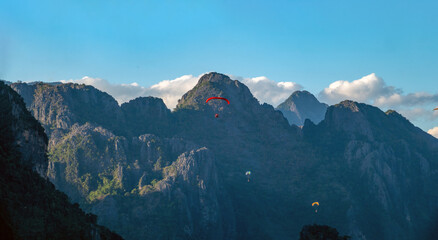 Microlight aircrafts gliding above the stunning karst rock formations in the Nam Song river valley, a popular actiuvity in the resort city of Vang Vieng, Vientiane Province, Laos