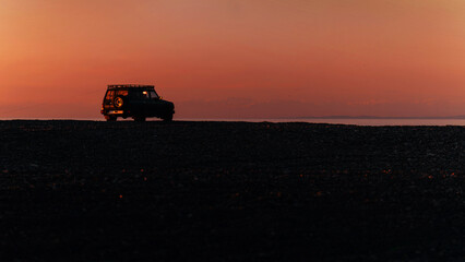 Fototapeta premium Travel offroad car on the coastline beach on the seaside during the evening sky