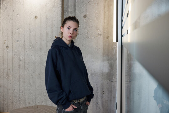 Portrait of young woman in office space with concrete and glass walls