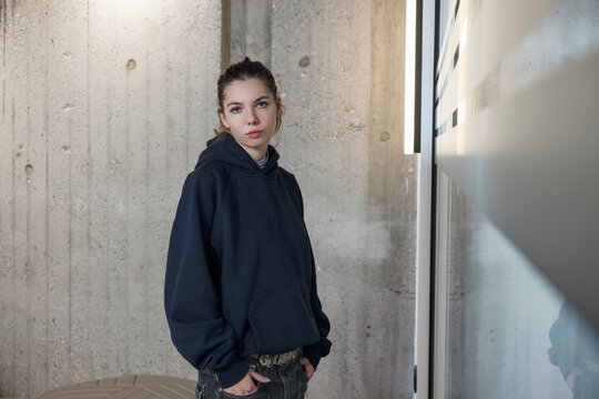 Portrait of young woman in office space with concrete and glass walls