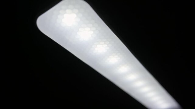 Modern LED light bar illuminates against a black background. Frosted plastic diffuser with a honeycomb texture covers the bright white diodes, creating a soft glow.