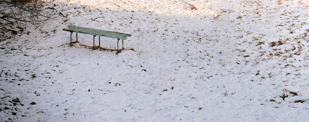 Lone turquoise bench in snowy winter field.