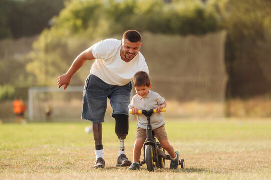 Teaching how to ride a bicycle. The amputee father is with his son on the field