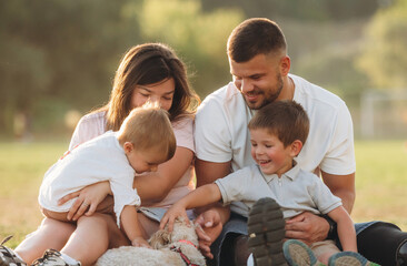 Resting by sitting on the ground. Mother, amputee father with prosthesis and kids are on the field