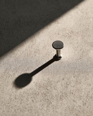 Minimal still life with single metal bolt and strong shadow