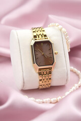 Closeup minimal fashion wristwatch for women on pink background.