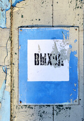 Vintage damaged exit sign in russian on distressed wall.