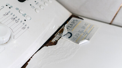 old broken top loading washing machine with rusty lid. washing machine and appliance repair, warranty sticker