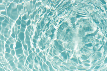 Blue water with ripples on the surface. Defocus blurred transparent blue colored clear calm water surface texture with splashes and bubbles. Water waves with shining pattern texture background.