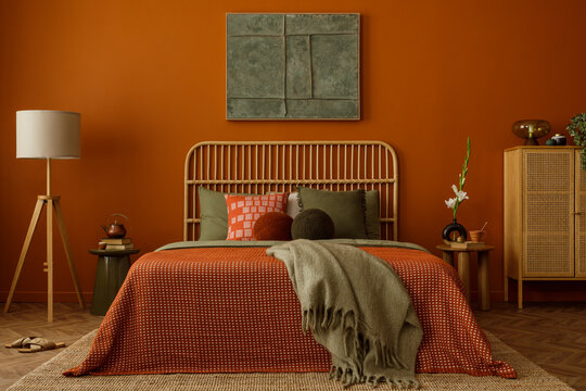 Stylish bedroom with an orange accent wall, rattan headboard and layered bedding in warm earthy tones. Cozy details add softness and comfort.