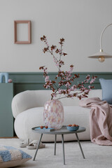 Spring composition of living room interior with mock up poster frame, boucle sofa, round coffee...