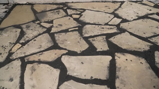 Flagstone patio construction in progress, workers installing natural stone pavers with sand and a rubber mallet