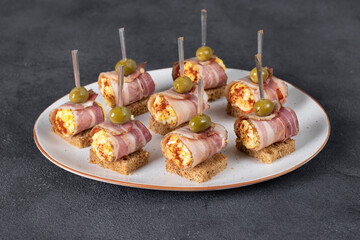 Canape with pancetta rolls with egg and processed cheese on bread toasts