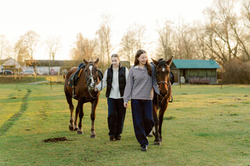 Two friends lead their horses through a lush green field as the sun sets, creating a serene atmosphere. The warmth of the evening light enhances their bond and the natural beauty around them.