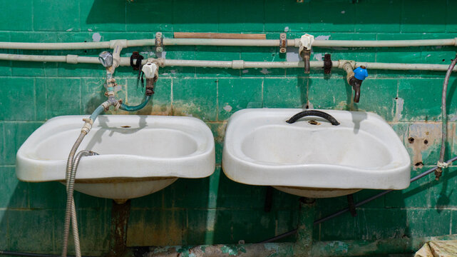 old bathroom in the dormitory, old plumbing, unsanitary conditions. broken cast iron sewer risers and pipes, hoses, washbasins, fungus on the ceiling. poor living conditions, renovation, rust, dirt