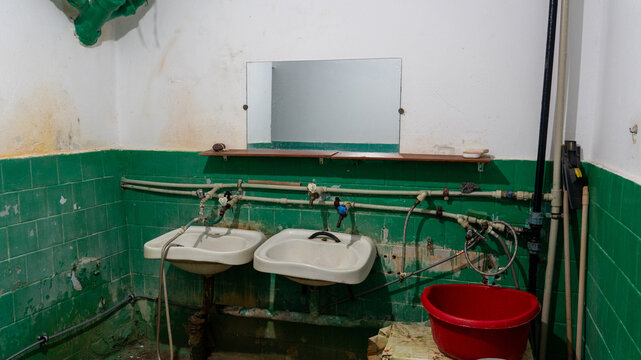 old bathroom in the dormitory, old plumbing, unsanitary conditions. broken cast iron sewer risers and pipes, hoses, washbasins, fungus on the ceiling. poor living conditions, renovation, rust, dirt