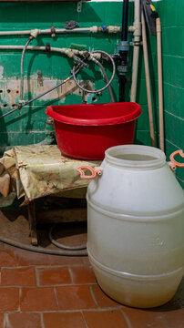 red basin and plastic water can in an old bathroom in a dormitory, old plumbing, unsanitary conditions. poor living conditions, renovation, rust, dirt