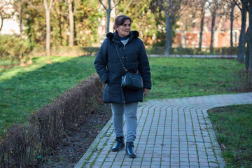 Fototapeta premium Elderly woman strolling in park