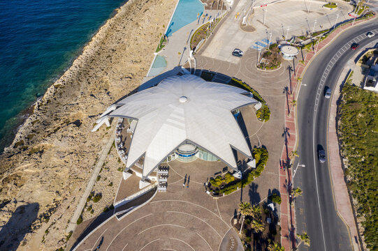 Aerial view of Qawra Pool near the rocky coast, the blue sea contrasting with the tan stone, Bugibba, St. Paul's Bay, Malta.