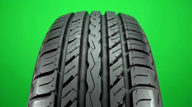 Isolated extreme close up of clean tire tread pattern rotating slowly on a seamless vibrant green screen background seamless background, compositing, black