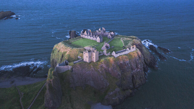 Aerial view of the majestic Dunnottar Castle standing proudly on a rocky headland against the dark blue sea, Stonehaven, Scotland, United Kingdom.