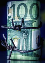 Euro banknote wrapped in barbed wire, symbolizing economic pressure, financial restriction, crisis, sanctions, and loss of economic freedom.