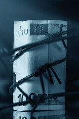 Economic warfare, sanctions and embargo busting concept. EU money wrapped in barbed wire against flag of European Union. Close up.