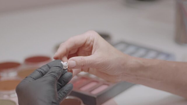 Closeup of artist assembling ball jointed doll, carefully attaching small handmade parts with precision and craftsmanship in creative workshop