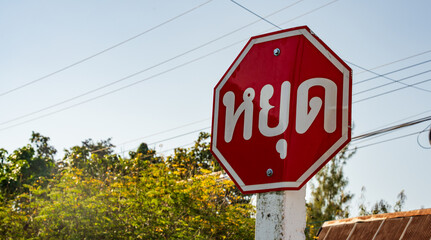 Thai stop sign written in Thai language beside rural road in northern Thailand