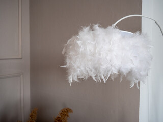 Elegant modern lighting fixture featuring a cloud-like white feather lampshade on a curved arc stand. A stylish decorative element for cozy contemporary home interiors and bedroom design. © Dmitry