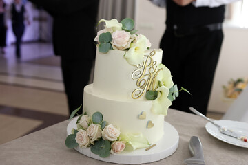 Two-tier wedding cake with fresh flowers and initials, minimalist elegant dessert for celebration event