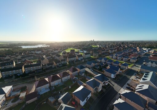 Aerial view of rooftops bask in the glow of the winter sun, a tapestry of brick and tile stretching towards the distant cathedral spires, Ely, England, United Kingdom.