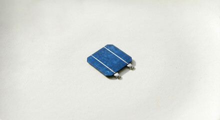 Small square blue solar cell isolated on white matte background. Minimalist renewable energy concept with single photovoltaic component.