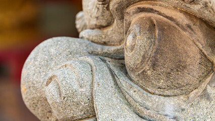 Close up detail of weathered stone guardian statue with carved features